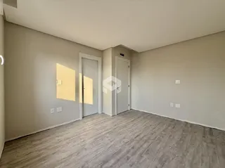 Imagem de um ambiente interno com piso de madeira e portas brancas.