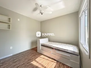 Quarto com cama e piso de madeira clara em um imóvel.
