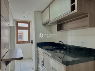 Vista interna de uma cozinha com armários e janela.