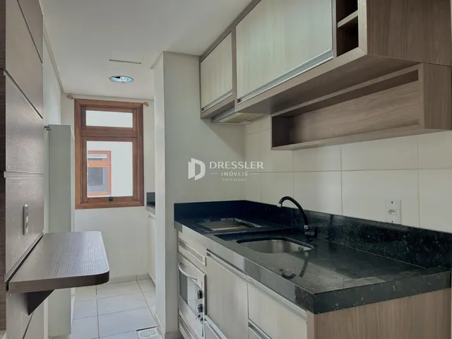 Vista interna de uma cozinha com armários e janela.