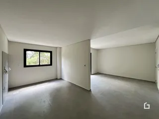 Imagem de um ambiente interno vazio com piso de concreto e uma janela.