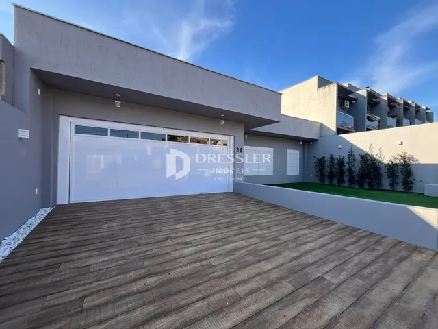 A fachada de uma residência em Lajeado, Brasil, com garagem e área externa de piso de madeira.