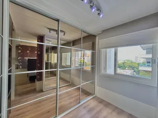 Interior de um ambiente com piso de madeira e divisórias de vidro.