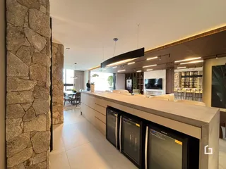 Interior de uma sala de estar moderna com ilha de cozinha e parede de pedra.