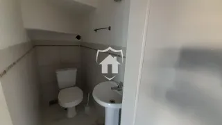 Foto de um banheiro com revestimento cerâmico e louças sanitárias brancas.