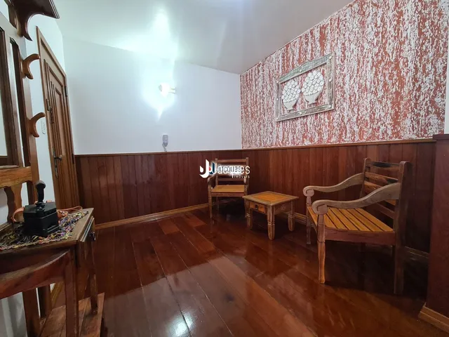 Sala de estar com piso de madeira escura e parede decorada.