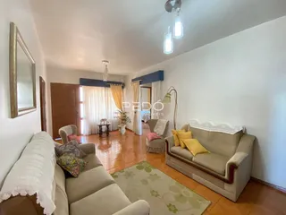 Sala de estar com móveis e piso de madeira em uma residência.