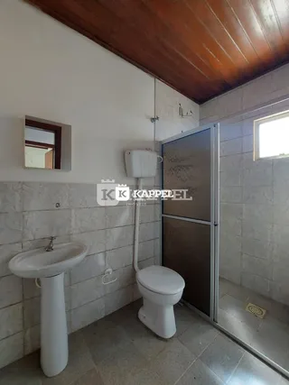 Foto de um banheiro com pia e vaso sanitário em um ambiente com teto de madeira.