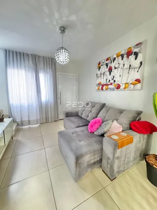 Sala de estar moderna com sofá cinza e piso claro.