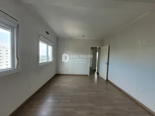 Sala de estar com piso de madeira e janelas em um imóvel em Lajeado.