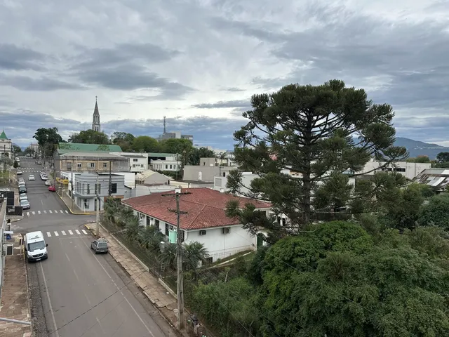 Vista externa de uma rua residencial com casas e uma igreja ao fundo em Lajeado.