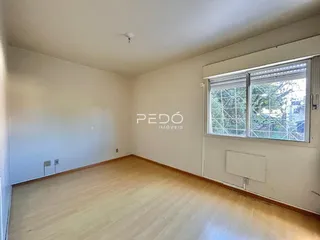 Ambiente interno de uma sala com piso de madeira clara e paredes brancas.