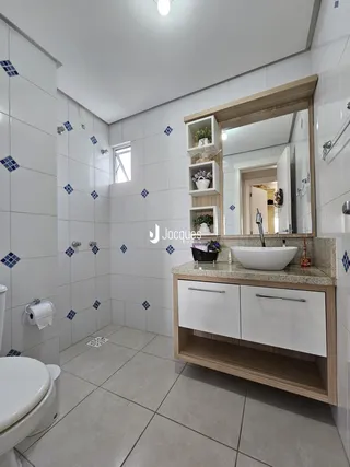 Banheiro com revestimento cerâmico nas paredes e piso claro.