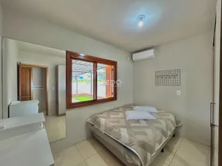 Quarto com cama e janela de madeira mostrando a vista externa.