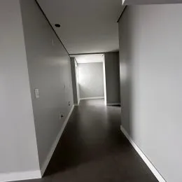 Corredor interno com paredes brancas e piso escuro.