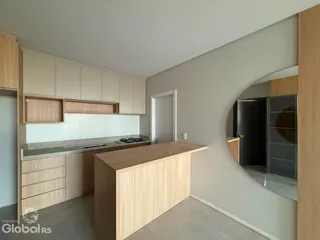 Cozinha moderna com armários de madeira clara e ilha de refeições.
