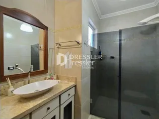 Foto de um banheiro com bancada e box de vidro.
