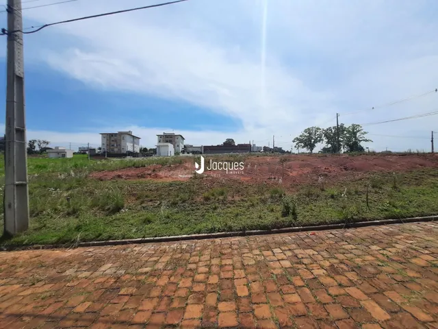 Vista de um terreno com vegetação e edifícios ao fundo.