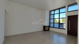 Ambiente interno amplo com paredes brancas e grande janela de vidro.