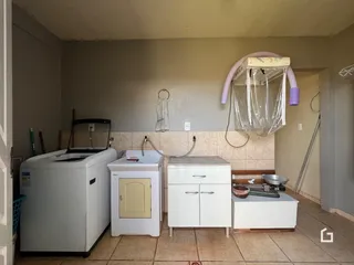 Foto de uma área de serviço com máquina de lavar e bancada.