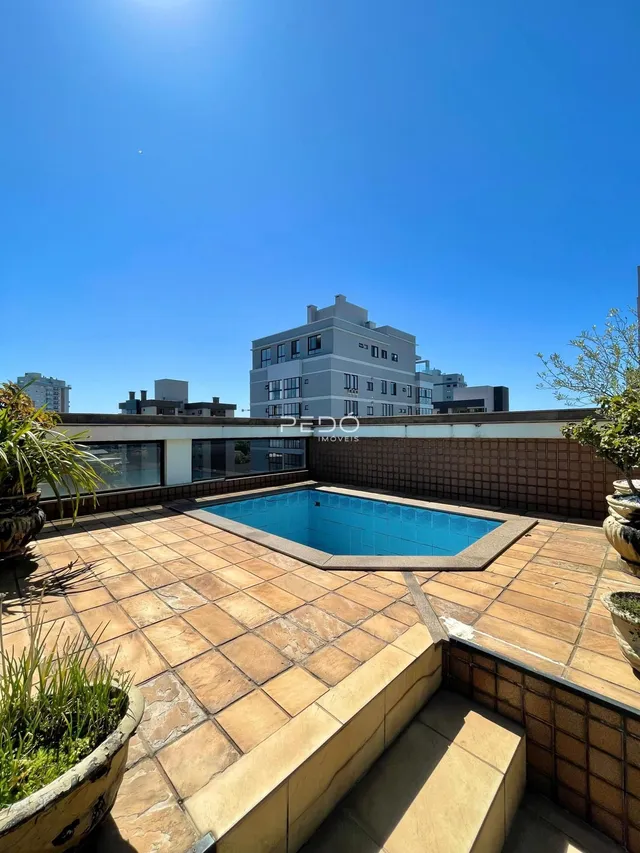 Vista de uma piscina externa em um terraço com piso de cerâmica.