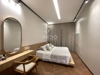 Quarto moderno com cama e armários em madeira clara.