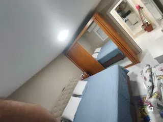 Quarto com cama azul e armário de madeira em um imóvel no Brasil.