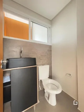 Foto de um banheiro interno com louças sanitárias e bancada.