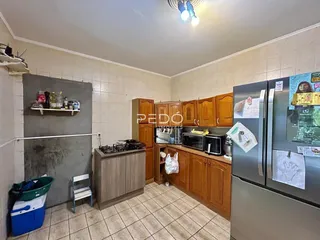 Foto interna de uma cozinha com armários de madeira e piso cerâmico.