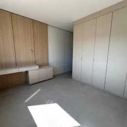 Ambiente interno com painéis de madeira e piso cinza.