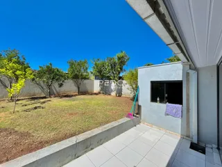 Vista externa de um quintal gramado com cerca e árvores