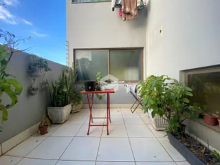 Área externa com plantas e piso cerâmico de um imóvel em Lajeado.