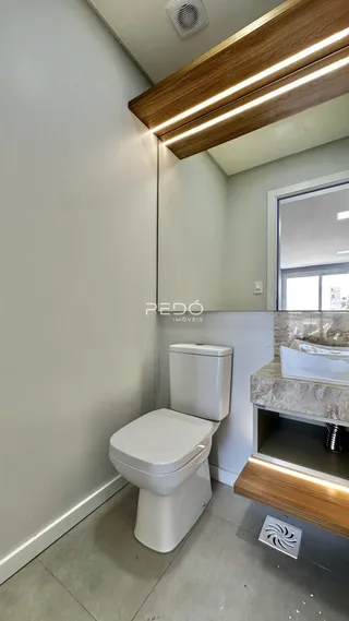 Foto de um banheiro interno com vaso sanitário branco e bancada de madeira.