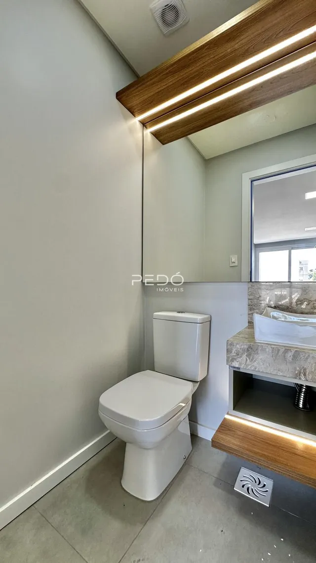 Foto de um banheiro interno com vaso sanitário branco e bancada de madeira.