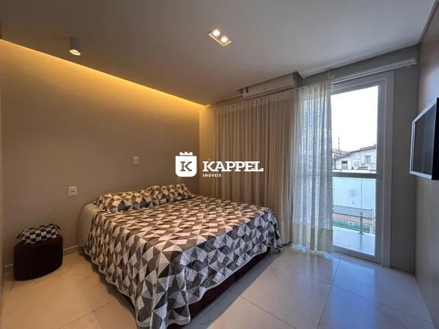 Quarto com cama grande e janela com cortinas claras.