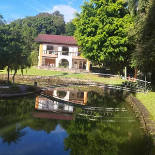Fachada de uma casa com jardim e ponte sobre um corpo d'água em Lajeado.