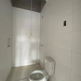 Foto de um banheiro com paredes brancas e azulejos.