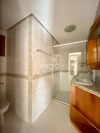 Foto de um banheiro com revestimento cerâmico e box de vidro.
