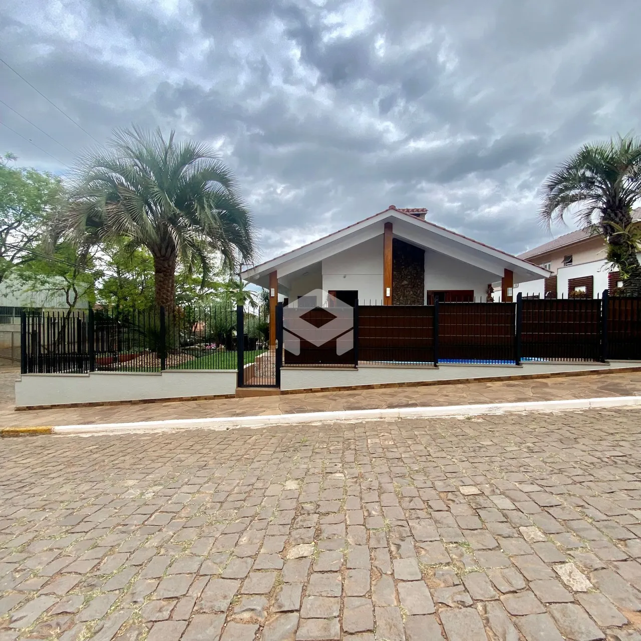 Fachada de uma casa em Lajeado, Brasil, com cerca e portão de madeira.