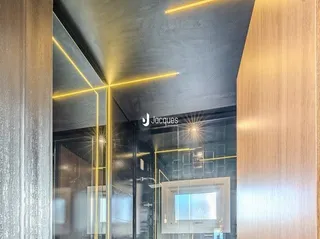 Vista interna de um corredor moderno com acabamentos em vidro e detalhes dourados.