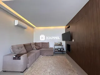 Sala de estar com sofá e televisão em ambiente moderno.