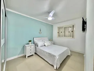 Um quarto com cama branca e paredes azul claro.
