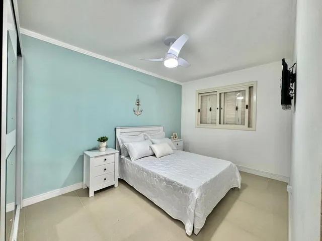 Um quarto com cama branca e paredes azul claro.