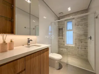 Banheiro moderno com box de vidro e revestimento de parede em tons de cinza.