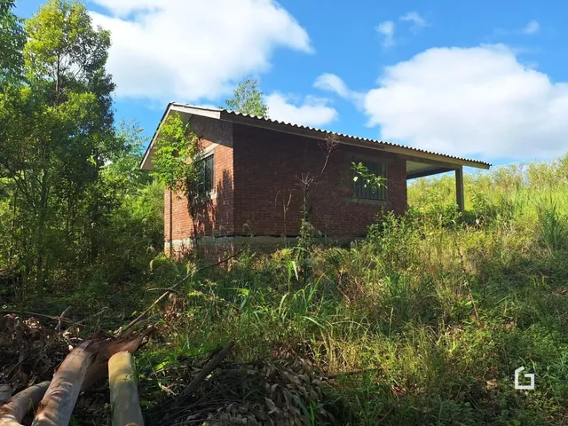 Fachada de um imóvel de tijolos em Lajeado, Brasil, cercado por vegetação densa.