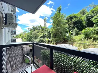 Vista da varanda com vegetação exuberante e céu azul.