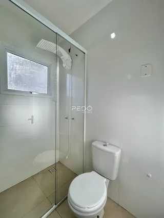 Foto de um banheiro com box de vidro e vaso sanitário em um imóvel.