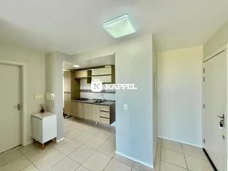 Uma foto interna mostra uma cozinha com armários de madeira e piso de cerâmica.