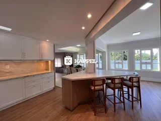 Cozinha moderna com armários brancos e bancadas de madeira em um ambiente iluminado.