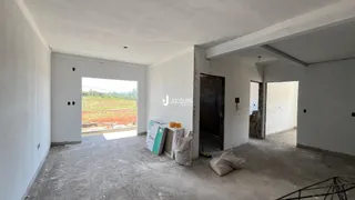 Interior de uma sala com piso de concreto bruto e paredes brancas.
